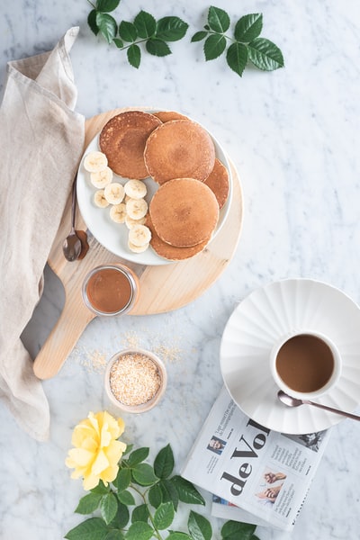 white ceramic mug with coffee beside brown cookies on brown wooden tray